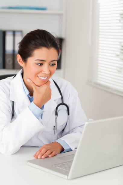 istock Beautiful female doctor working with her laptop while sitting 824852652
