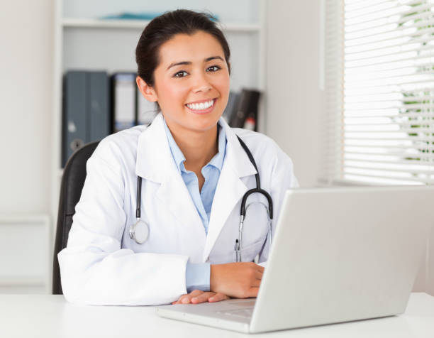 istock Good looking female doctor working with her laptop while posing 824852748