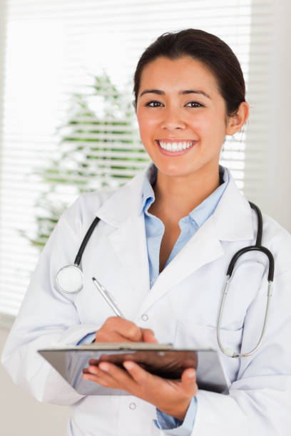 istock Attractive female doctor with a stethoscope writing on a notebook while standing 824852982