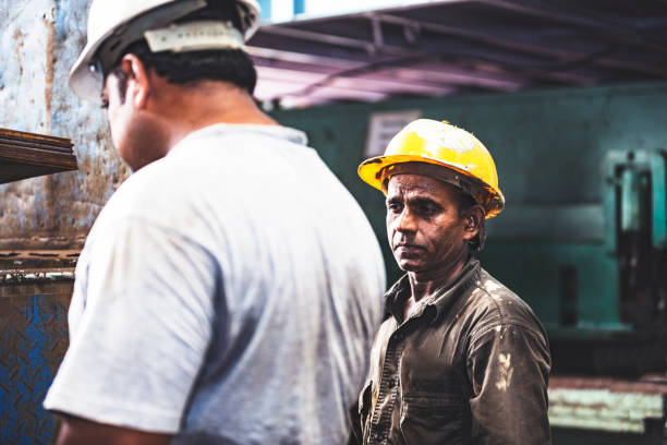 Tired factory employees looking into what they need to do next on their project.