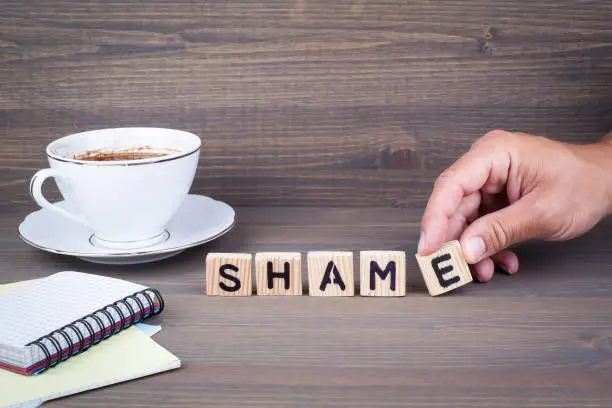 Photo of shame. Wooden letters on dark background