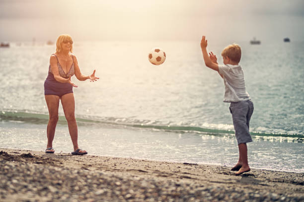 istock Little boy playing catch with grandmother on beach 824879310