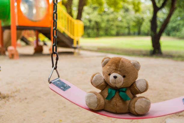 istock Lonely bear doll sit on a swing in amusement park 824880478