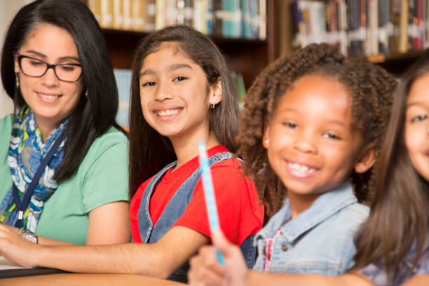 istock Teacher, mentor helps elementary-age schoolgirls with homework. 824882942
