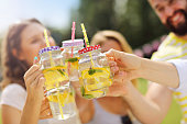 Group of young people cheering and having fun outdoors with drinks