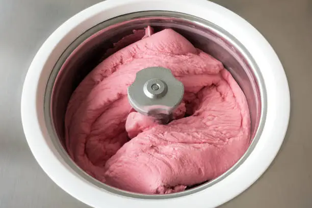 Homemade raspberry ice cream churning in a small professional  ice cream machine.