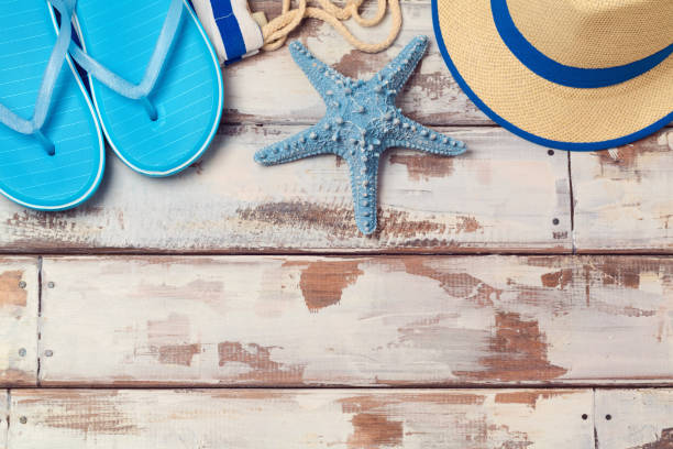 istock Summer vacation background with flip flops, starfish and hat on wooden board. View from above 824907444
