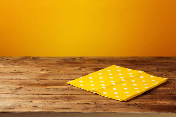 Empty wooden table with tablecloth over yellow background. Autumn season concept