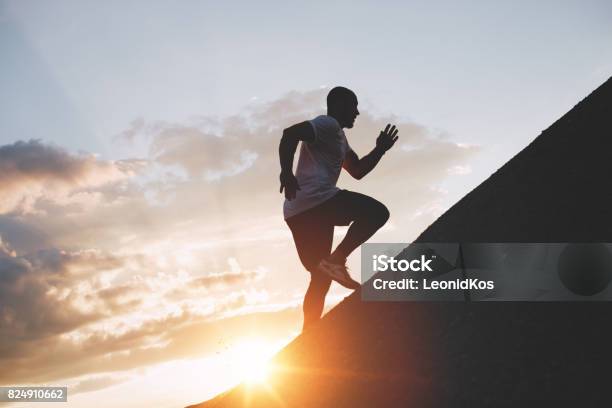 Male Runner Trains In An Ascent To A Mountain Athlete Runs Through The Mountains And Hills At Sunset Stock Photo - Download Image Now