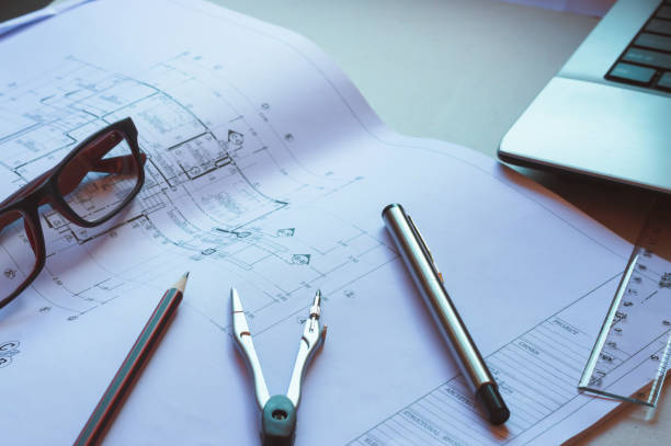 istock Divider, pencil, pen, ruler, glasses and smartphone and blueprint on table top.Table top view of Engineers table at office workplace.selective focus. 824912868