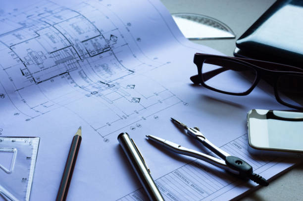 istock Divider, pencil, pen, ruler, glasses and smartphone and blueprint on table top.Table top view of Engineers table at office workplace.selective focus. 824913150