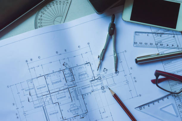 istock Divider, pencil, pen, ruler, glasses and smartphone and blueprint on table top.Table top view of Engineers table at office workplace.selective focus. 824913942