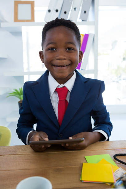 istock Boy as business executive holding digital tablet 824928782