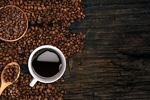 Coffee background, top view with copy space. White cup of coffee and, ground coffee, coffee beans on dark wooden backgroundCoffee background, top view with copy space. White cup of coffee and, ground coffee, coffee beans on dark wooden background