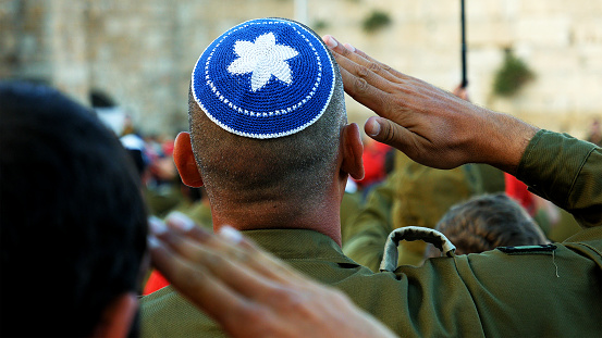 Jerusalem, Israel - May 25, 2017: Israeli soldier military man saluting to the Western wall in Jerusalem. Western wall or Wailing wall or Kotel is the most sacred place for all jewish people.