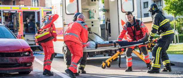 Firefighters helping rescue team Paramedic team around stretcher with injured person pushing it into ambulance vehicle, firefighters are helping them. stretcher stock pictures, royalty-free photos & images