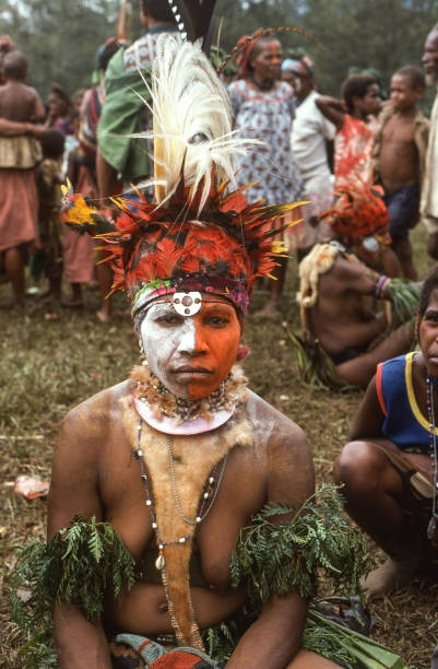 Sing-Sing in Kuchiano, Papua New Guinea. Traditionally dressed people. This SingSing where hundreds of people from surroundings area gather is held every 7th year. Decorations with feathers from paradise birds. Mother carrying child in the foreground,