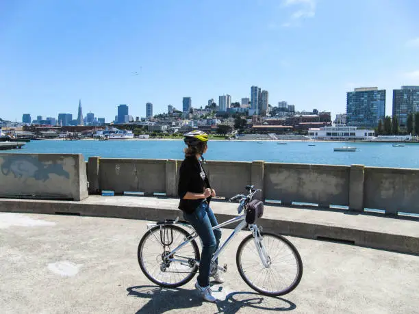 Young woman on bicycle looking at cityscape or skyline of San Francisco