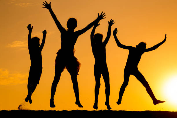 istock silhouette of four jumping kids against sunset 824959100
