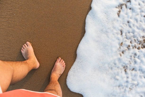 istock Man's feet seen from above with sea water. 824959110