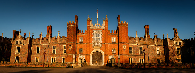 Panorama shot of the facade of the Hampton Court Palace with the Union Jack in London, England, UK during sunset