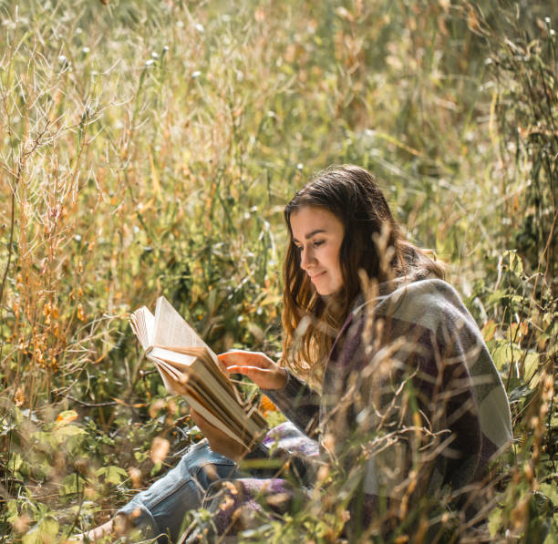 istock young girl on a field reading a book 824970854