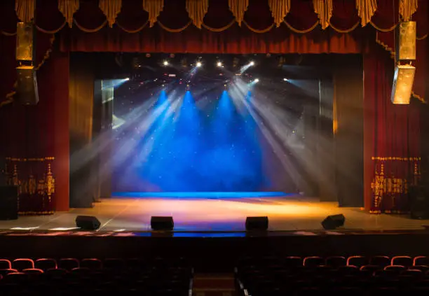 Photo of An empty stage of the theater, lit by spotlights and smoke