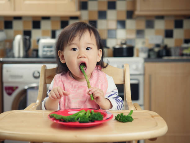 baby girl eating at home baby girl eating at home eating asparagus stock pictures, royalty-free photos & images