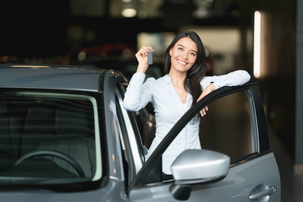 glückliche frau betrieb schlüssel für ihr neues auto beim händler - car car rental car dealership key stock-fotos und bilder