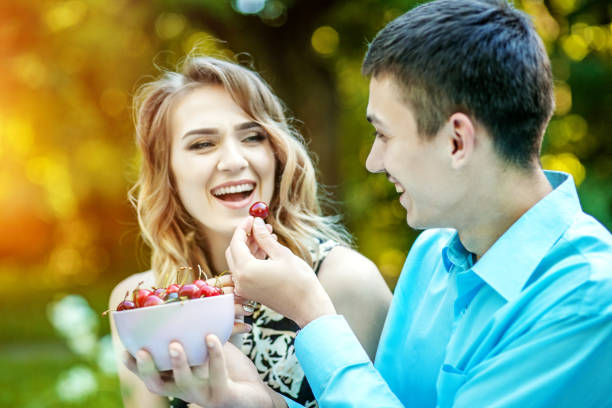 istock A young lovers couple eats cherries. Laughing in the park. The c 824987362