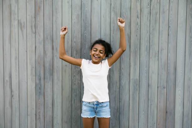 istock Happy girl standing at wall with raised hands 824999152