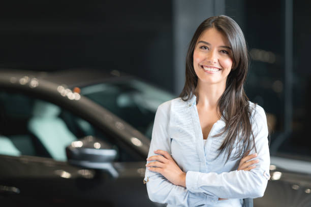 happy woman buying a car at the dealership - reduction looking at camera finance business imagens e fotografias de stock