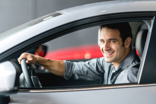 istock Happy man test driving a car and looking at the camera smiling 825001750