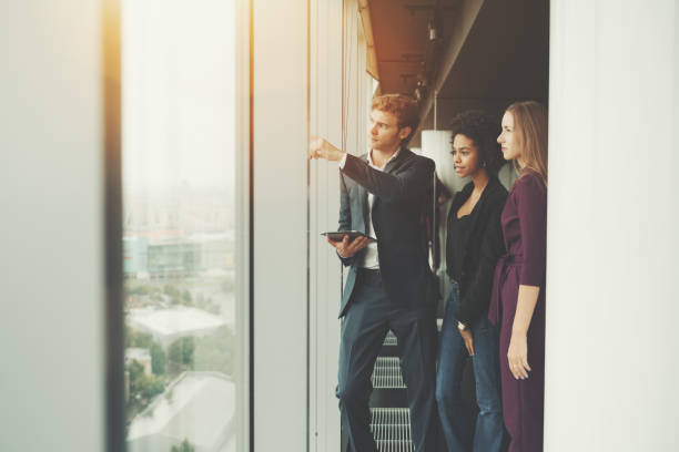 istock Three business persons near office window 825005998