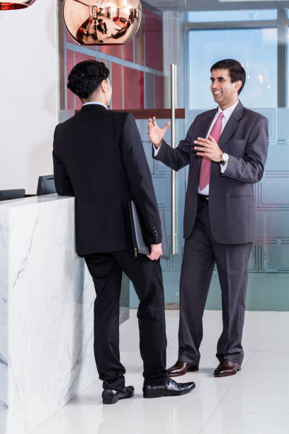 istock Manager and affiliate leaning at front desk of office 825008338