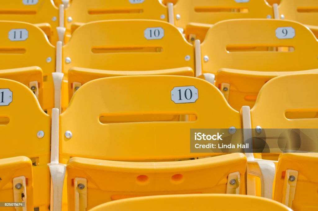 Yellow  Seats Yellow numbered empty seats. Agricultural Field Stock Photo