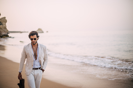 Young handsome man walking at the beach