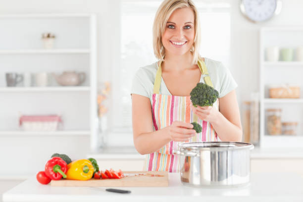 istock Woman cooking broccoli looks into the camera 825030572