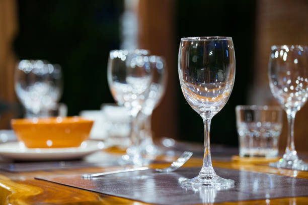 istock Close-up empty wine glasses on wooden table. Part of dining table interior 825034168