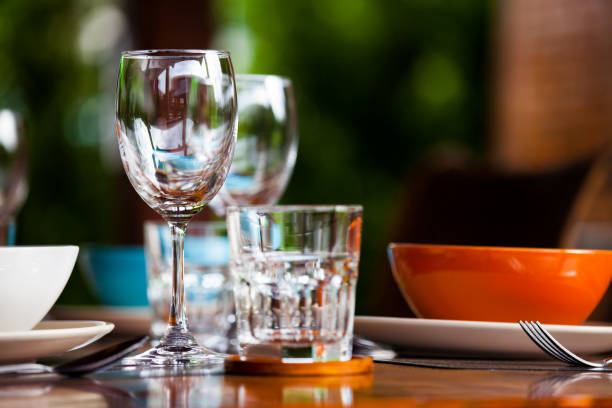 istock Close-up empty wine glasses on wooden table. Part of dining table interior 825034188