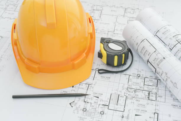 istock architects workplace - architectural blueprints with measuring tape, safety helmet and tools on table. top view 825049240