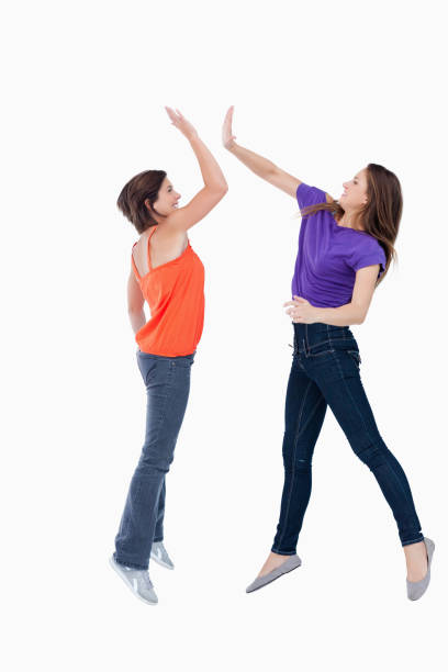 istock Two teenagers jumping while trying to join their hands 825050352