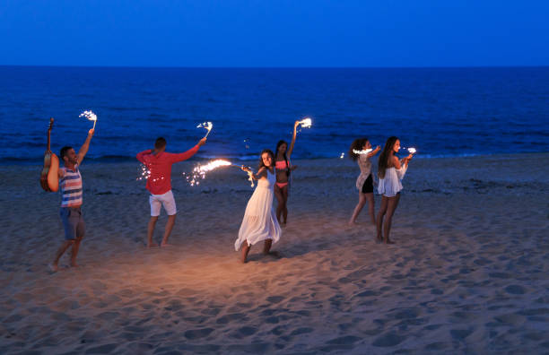 istock Friends dancing and celebrating with flaming torches on beach 825058710
