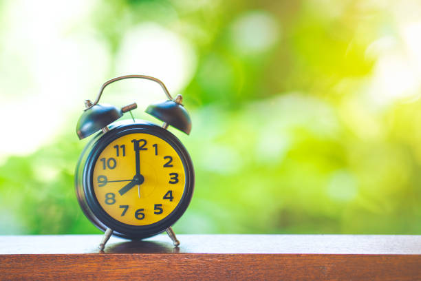 istock Black Desk Clock with Yellow Screen on Wooden Table 825060936