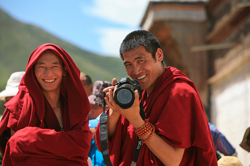 Labrang, China - August 07, 2011: Monks taking photos at Labrang Monastery. Founded in 1709, this is one of the six great monasteries of the Gelug school of Tibetan Buddhism and one of the most visited and revered by visitors. It hosts thousands of monks and is the most important monastery outside the Tibet Autonomous Region. Labrang is located in Xiahe County, Gannan Tibetan Autonomous Prefecture, Gansu, in the traditional Tibetan area of Amdo.