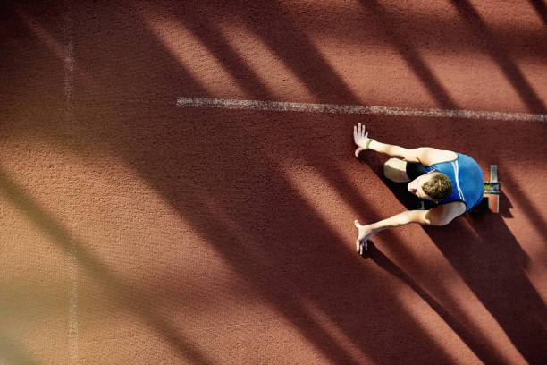 Training for Paralympics Above view image of dedicated amputee athlete with prosthetic leg in start position on running track paralympic games stock pictures, royalty-free photos & images