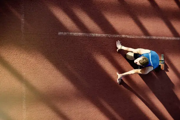 Above view image of dedicated amputee athlete with prosthetic leg in start position on running track