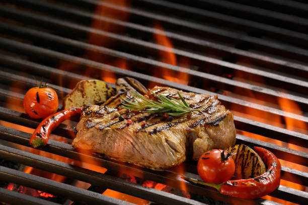 istock Grilled pork steak with vegetable on the flaming grill 825078832