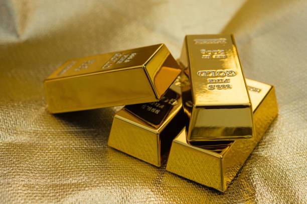 four pieces of gold bars on a golden background stock photo