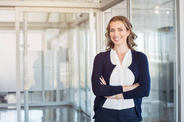 Successful mature businesswoman Portrait of mature beautiful business woman in the office looking at camera. Business executive standing in modern office with big smile. Cheerful mid businesswoman with copy space. woman waist up stock pictures, royalty-free photos & images